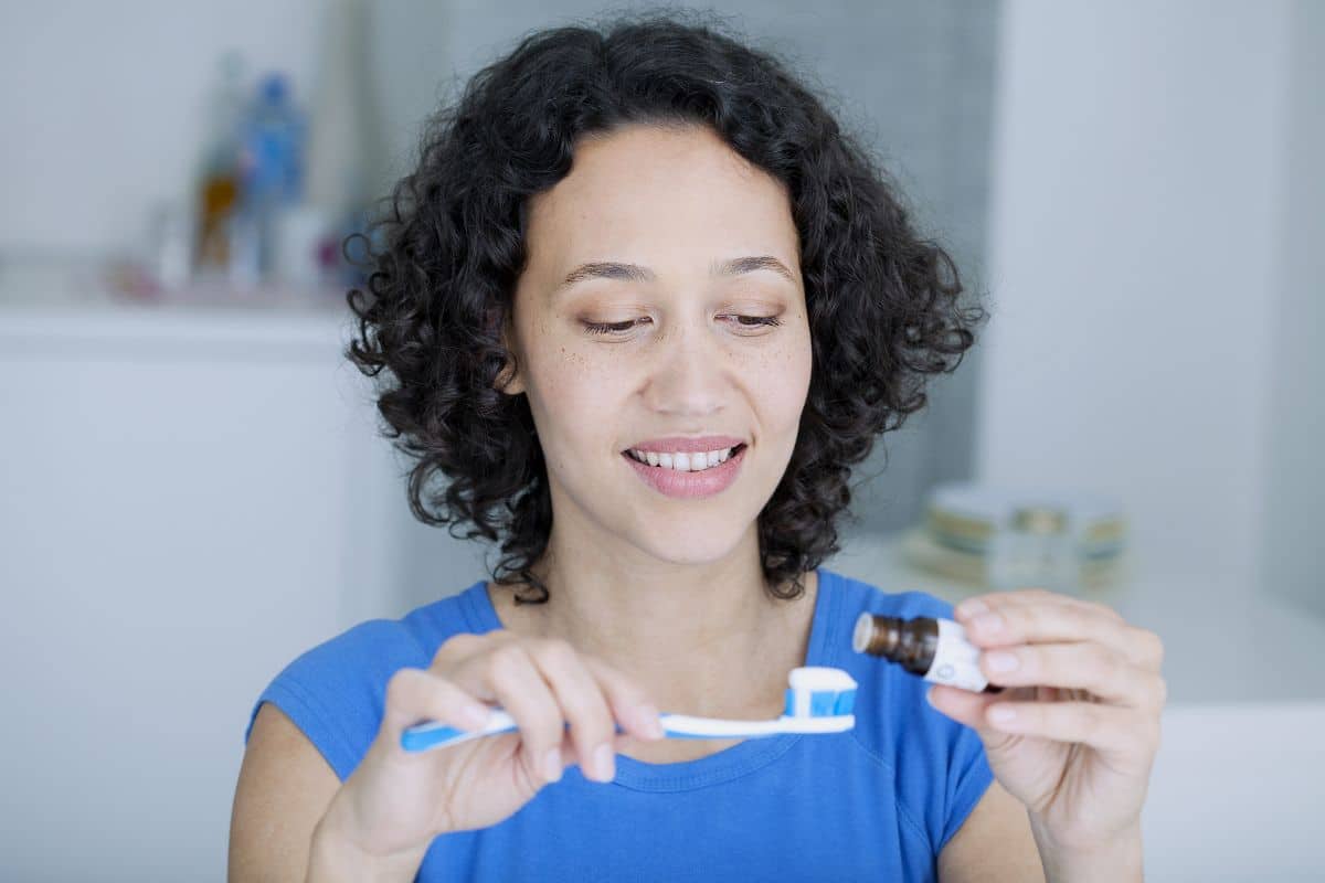 3 Calming Dental Products Woman in blue shirt holding dental floss in bright clinical setting, smiling.